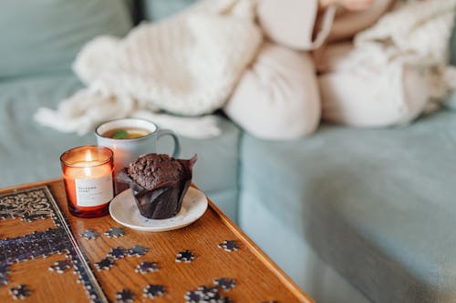 A Scented Candle Beside a Chocolate Muffin