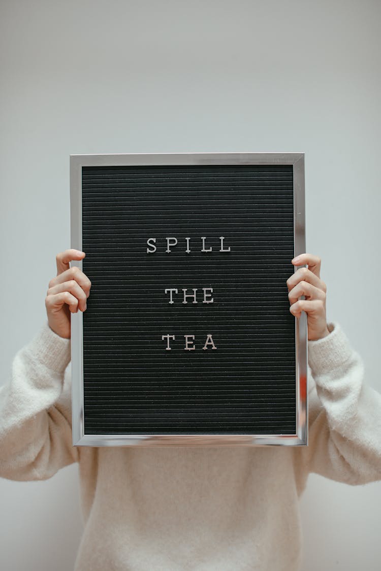 A Person Wearing Sweater Holding A Letter Board Covering Her Face