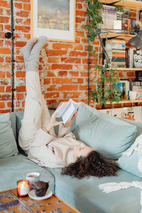 Woman Reading a Book While Lying on the Sofa