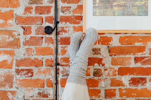 Free Person's Legs Against the Brick Wall Stock Photo