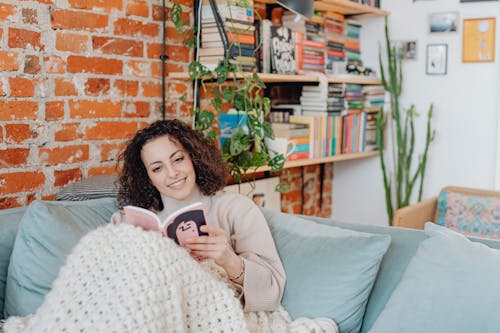Free Woman in Beige Sweater Sitting on a Couch Stock Photo