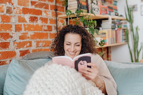 Smiling Woman in Beige Sweater Holding a Book