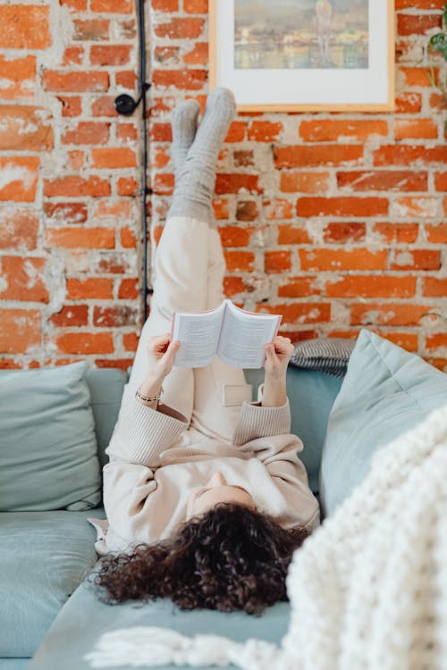 Woman Lying on Sofa Near Brick Wall