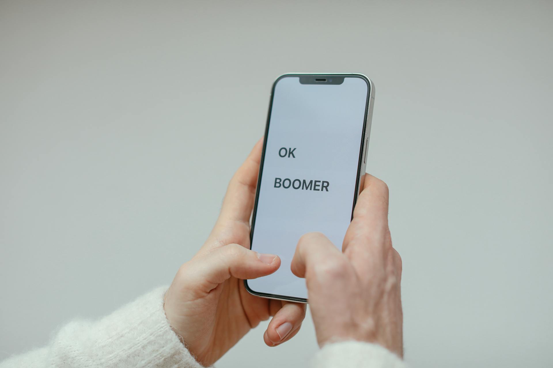 A Person in White Sweater Holding a Cellphone with Message