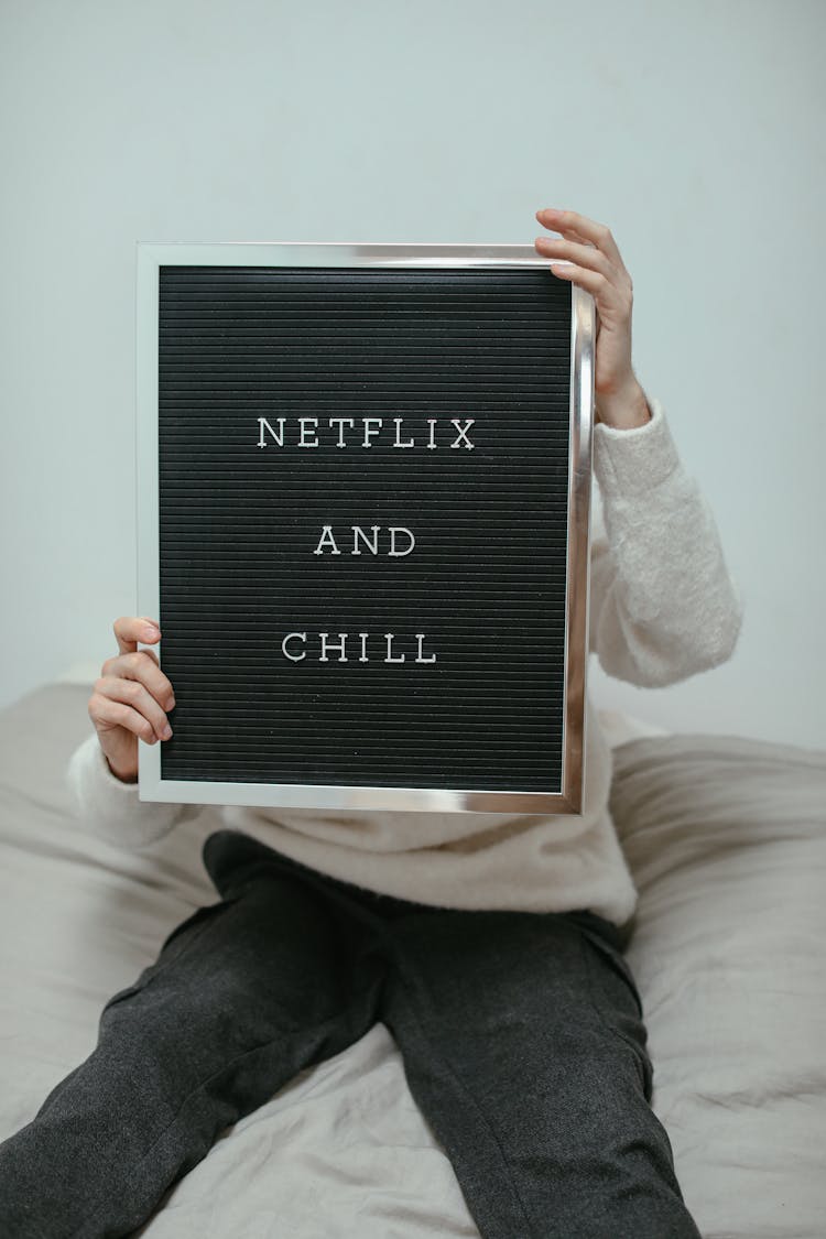 A Person In White Sweater Sitting On A Couch While Holding A Letter Board