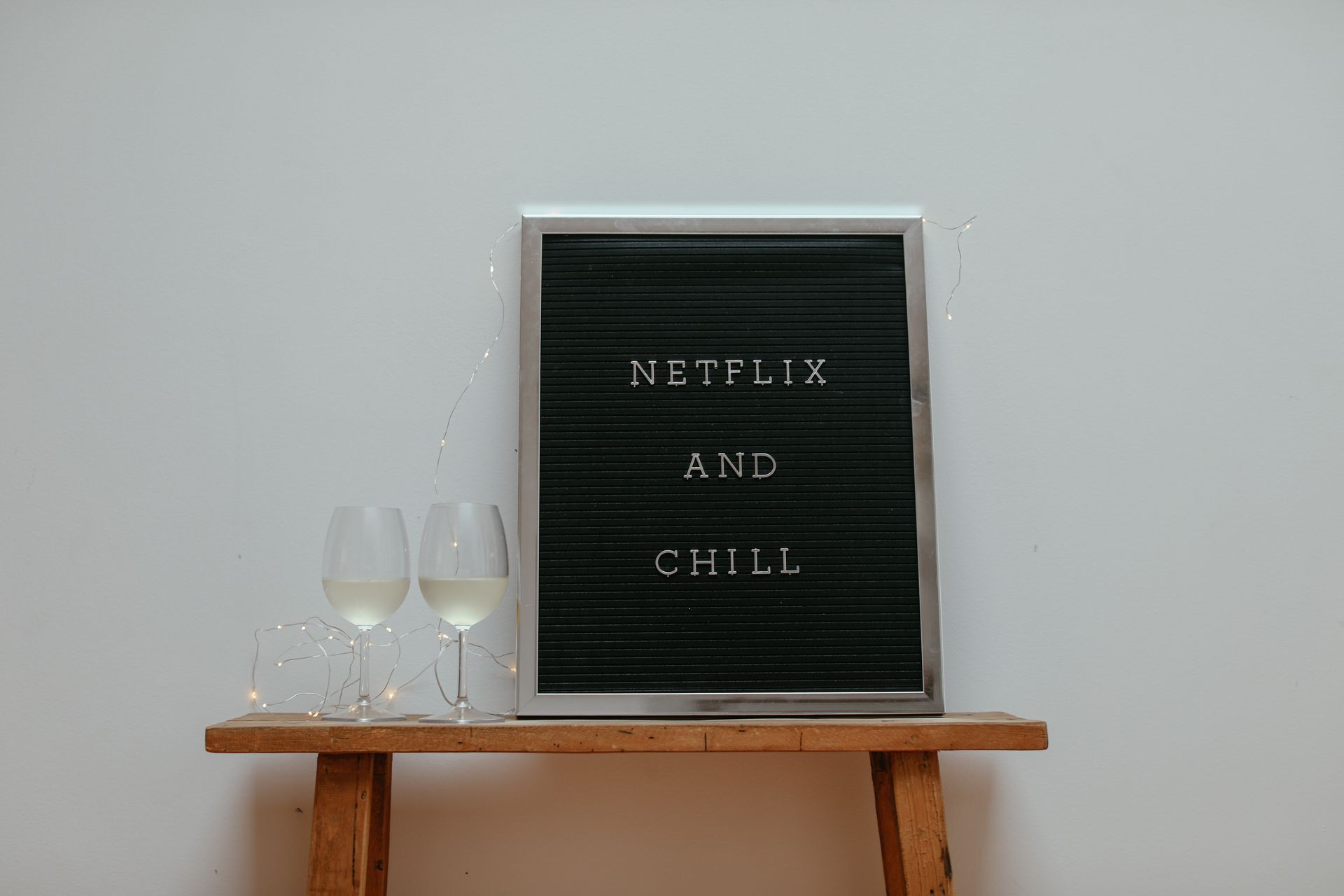 Board with Message and Two Glasses with White Wine on a Wooden Stool
