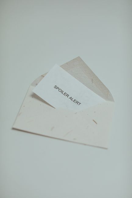 A simple and elegant envelope with a 'Spoiler Alert' card inside on a light background.