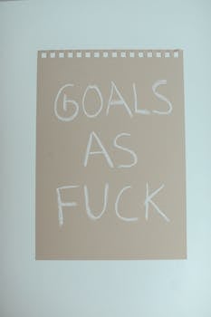 Motivational phrase 'Goals as Fuck' on a simple, minimalist paper background.