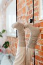 A Person Wearing Brown Socks Resting His Feet on the Brick Wall