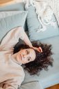 Woman in Turtle Neck Sweater Lying Near the Throw Pillows while Looking Afar