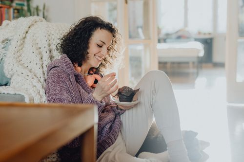 Free Woman enjoying a chocolate muffin in a cozy home setting, embodying leisure and indulgence. Stock Photo