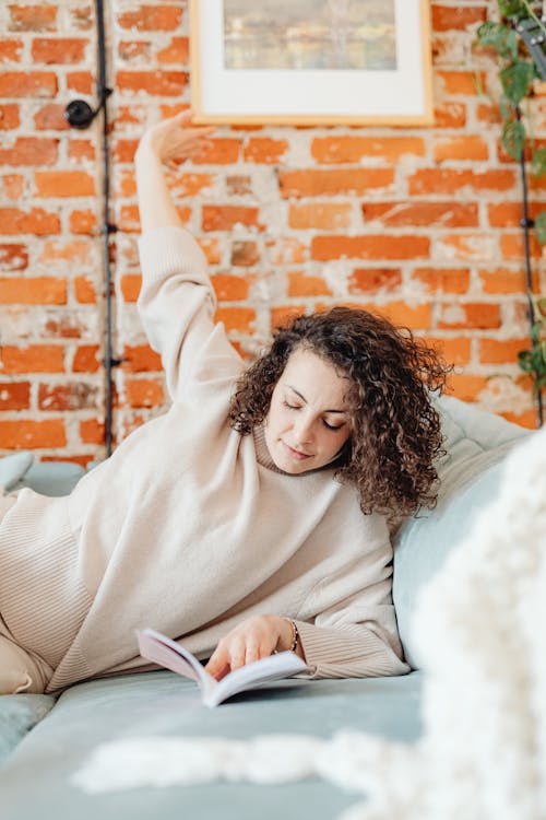 Free Woman Stretching Her Arm While Reading a  Book Stock Photo