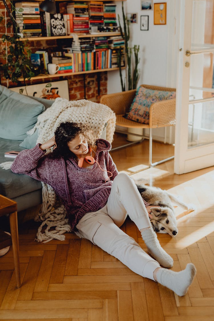 Woman Sitting On The Floor In A Living Room With Her Dog 