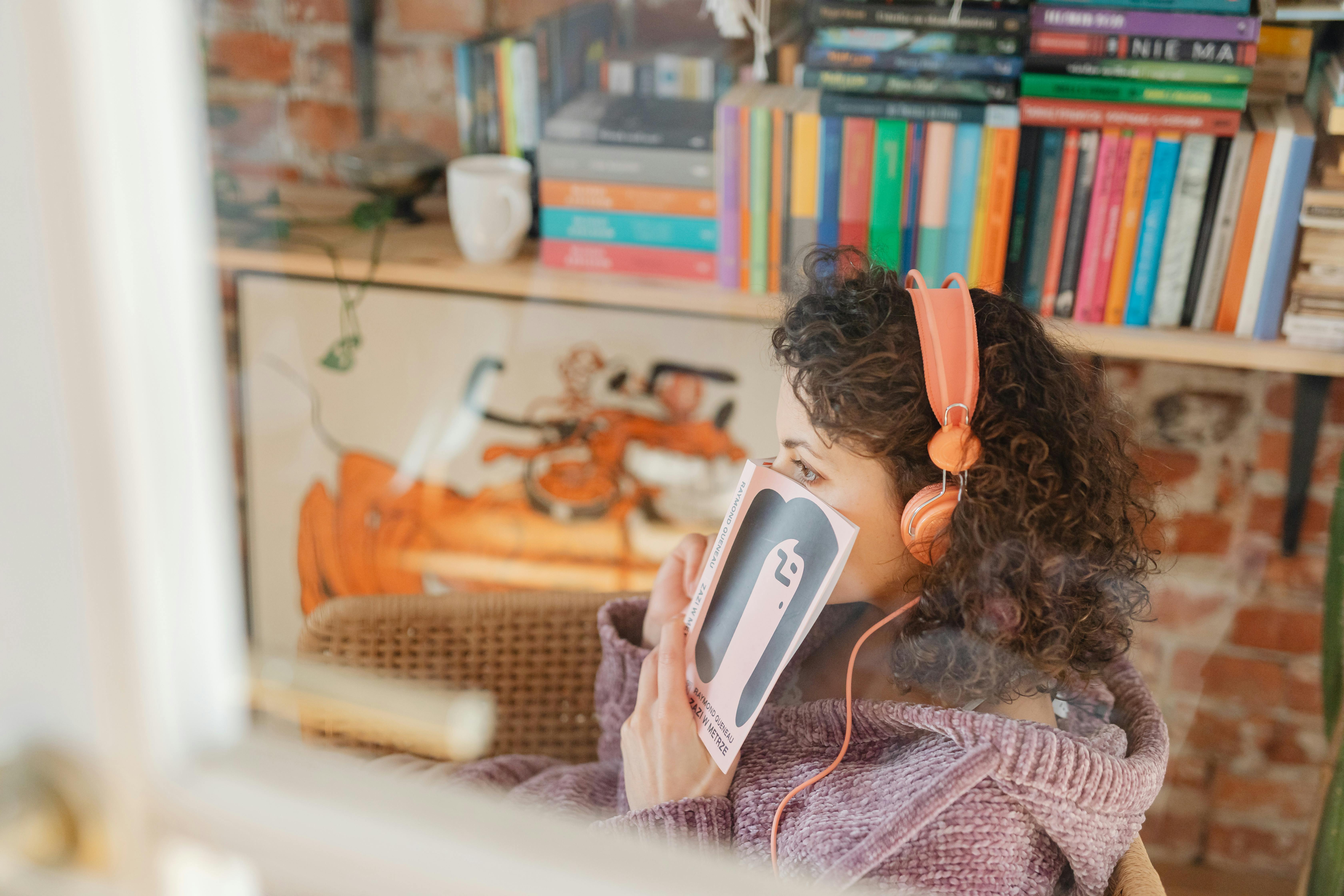 photo of a woman wearing headphones and holding a book