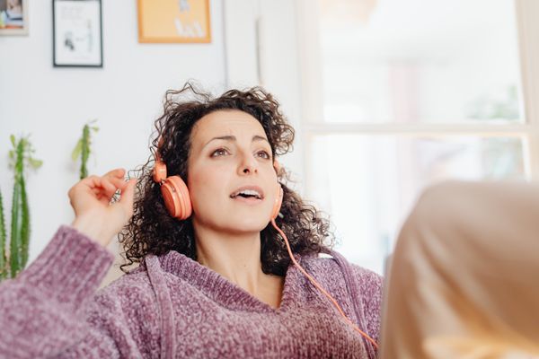 Femme écoutant une séance d'hypnose avec un casque, détendue chez elle