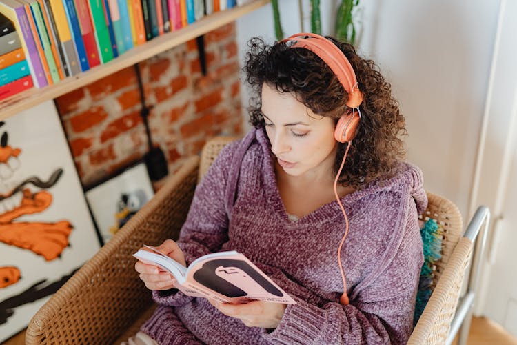 Woman With Headphones Reading A Book At Home