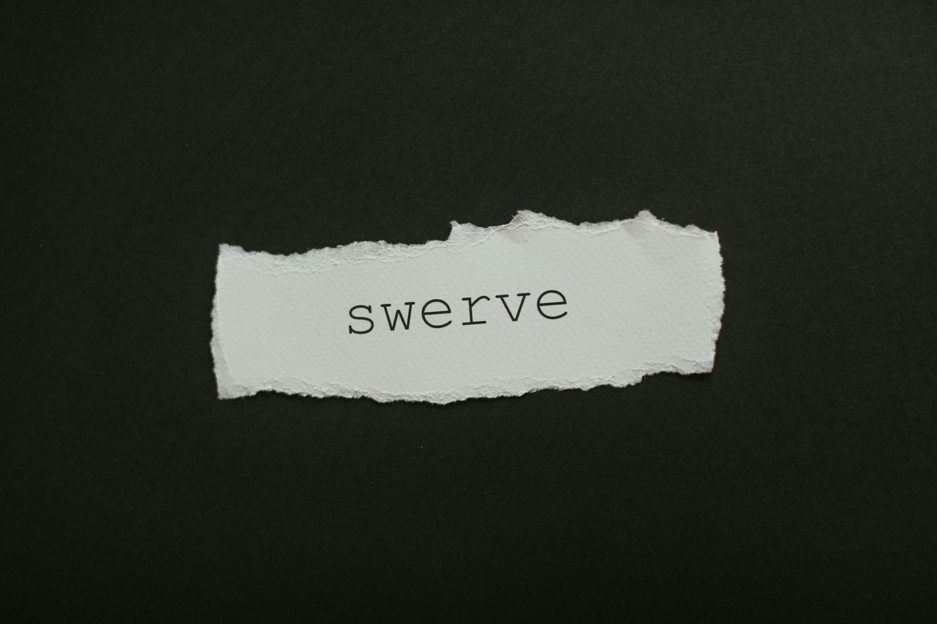 Close-up of torn paper with the word 'swerve' on a black background, ideal for concepts of change and direction.