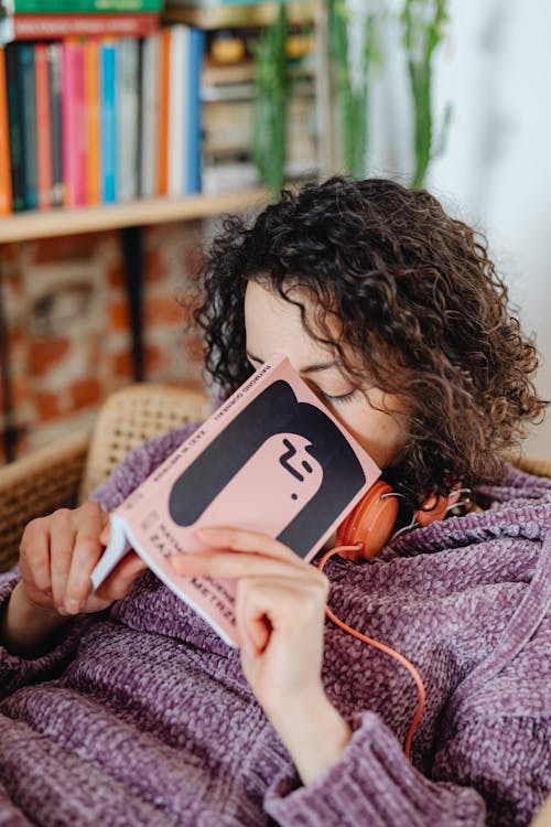 Close-Up Photo of a Woman with Curly Hair Sleeping while Holding a Book