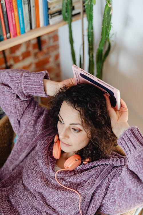 Free High-Angle Shot of a Woman Holding a Pink Book Behind Her Head Stock Photo