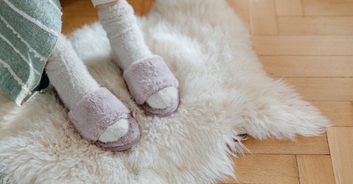 Warm and cozy feet in plush slippers resting on a soft fur rug for relaxation.