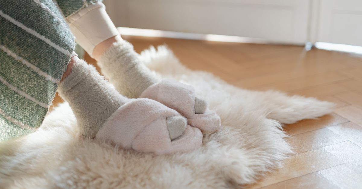 Warm slippers and socks on a fluffy rug by the sunlight, creating a cozy home atmosphere.