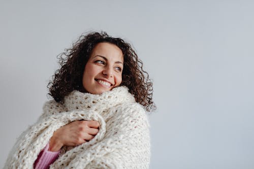 Free Portrait of Woman Wrapped in a White Knitted Scarf against Gray Background Stock Photo