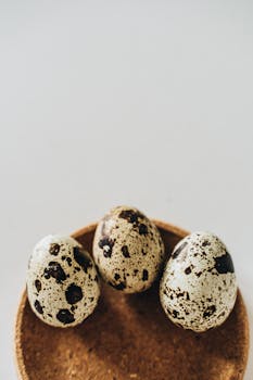 A minimalist arrangement of three quail eggs on a cork surface, perfect for culinary themes.