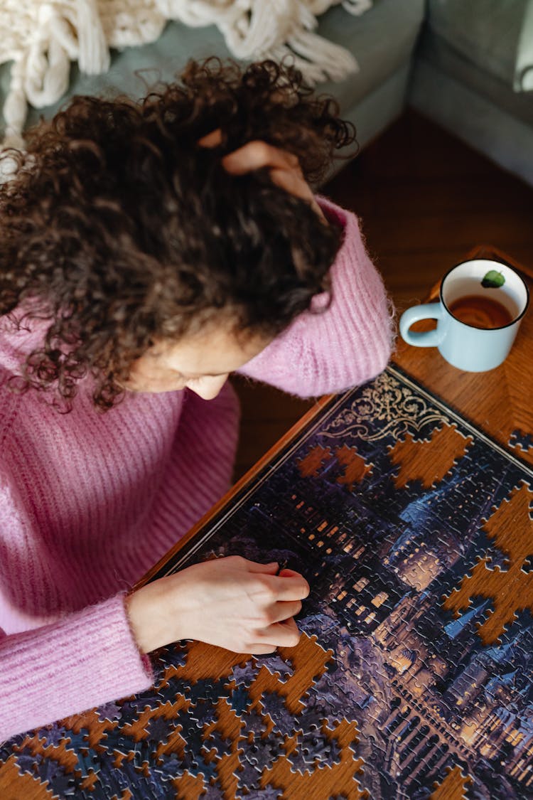 High Angle View Of A Woman In A Pink Polo Neck Sweater Solving Puzzles