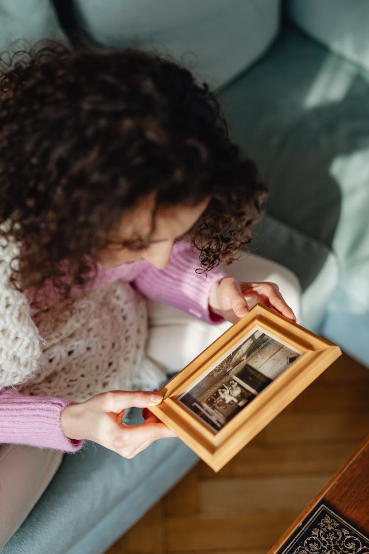 Young Woman Looking At Framed Photograph