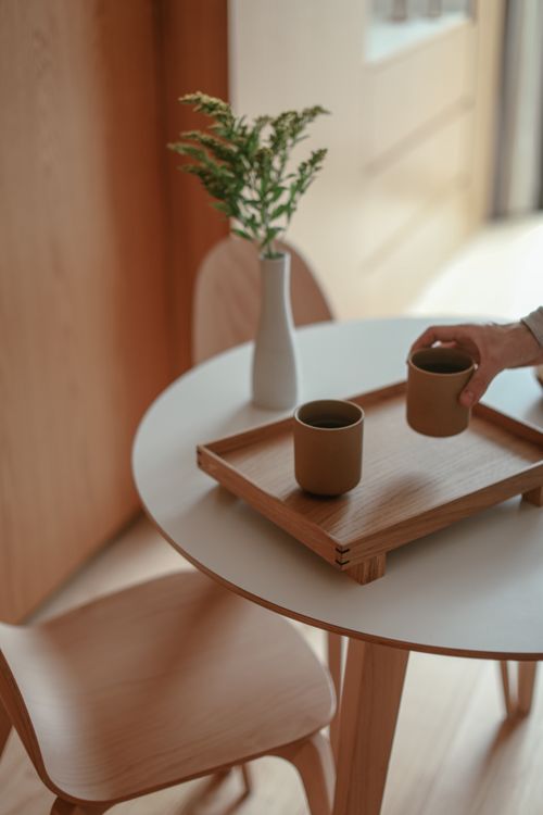 Free A cozy, minimalist coffee setup with cups on a wooden tray and a vase on a table. Stock Photo