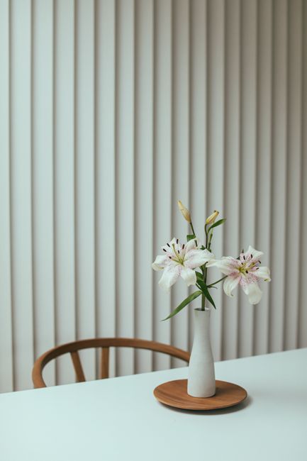 A minimalist still life featuring white lilies in a vase on a modern table, highlighting elegance and simplicity.