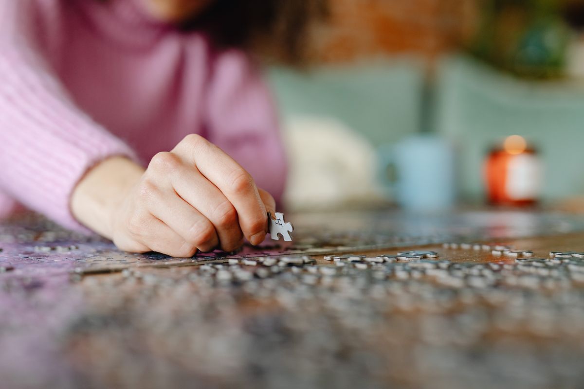 Adult working carefully on a detailed tabletop jigsaw puzzle