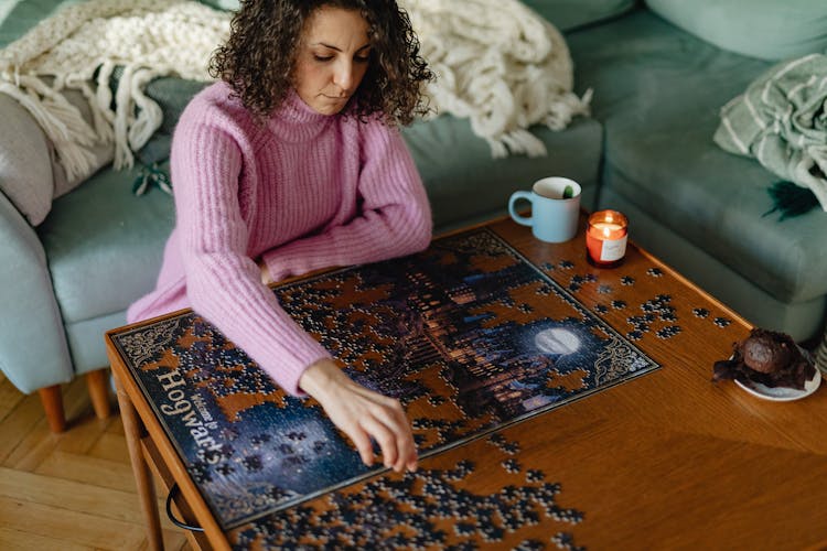 Woman Sitting On The Floor And Putting Puzzle Together On A Coffee Table 