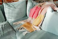 A warm colorful blanket draped on a teal sofa, adding cozy charm to a living room interior.