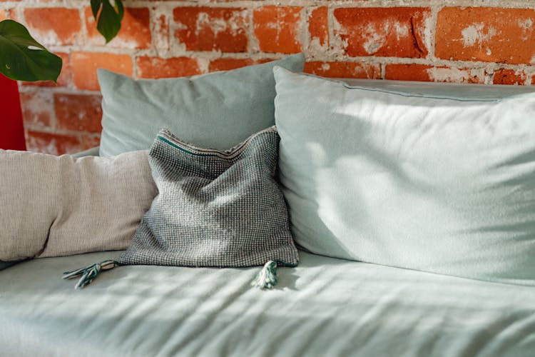 Teal Sofa With Pillows And Brick Wall