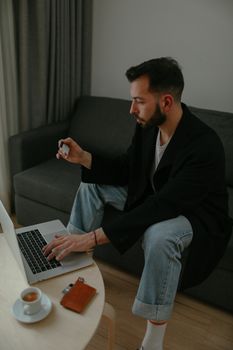 Adult man sitting on couch, using laptop for online shopping with credit card.