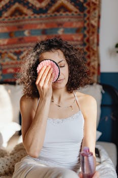 Woman using a pink reusable makeup pad during her skincare routine.