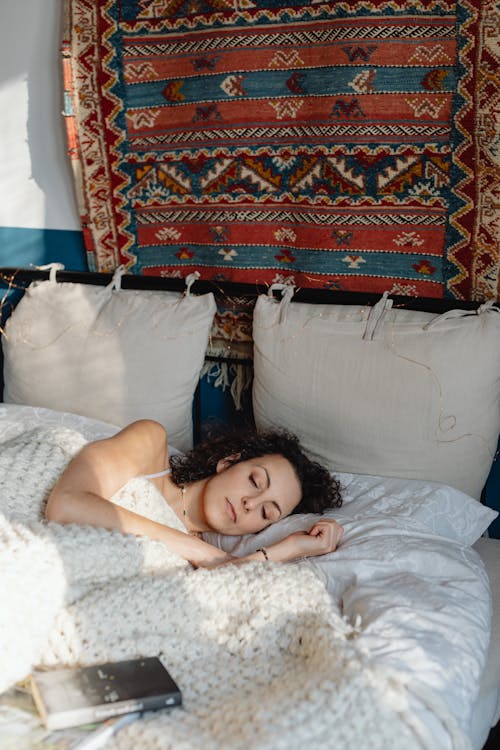 Free Woman Sleeping in Bed with a Book Next to Her  Stock Photo