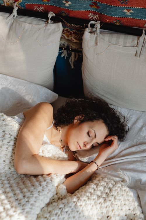 Free Serene scene of a woman sleeping peacefully in bed with a knitted blanket. Stock Photo