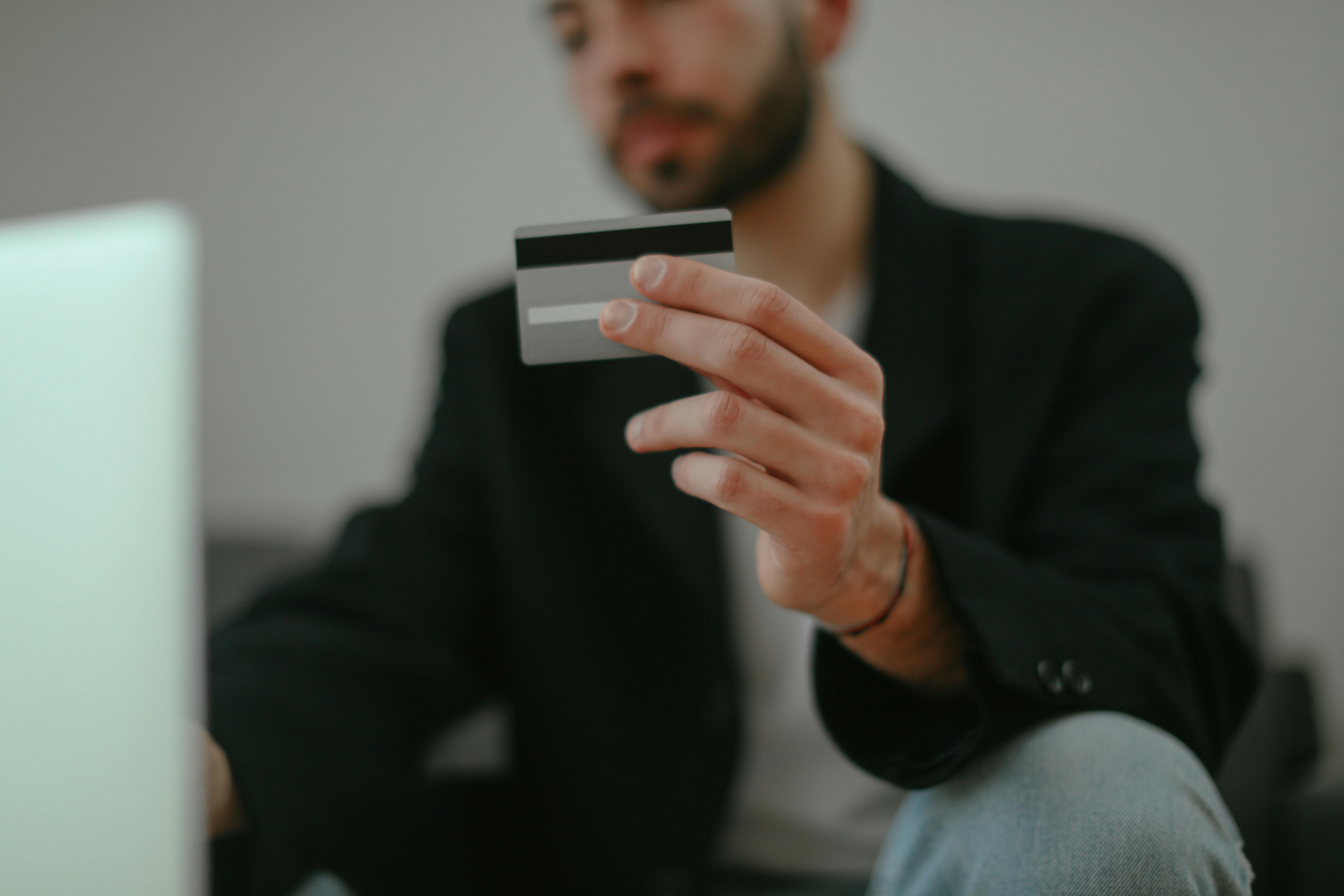 hand of a man holding a credit card towards camera