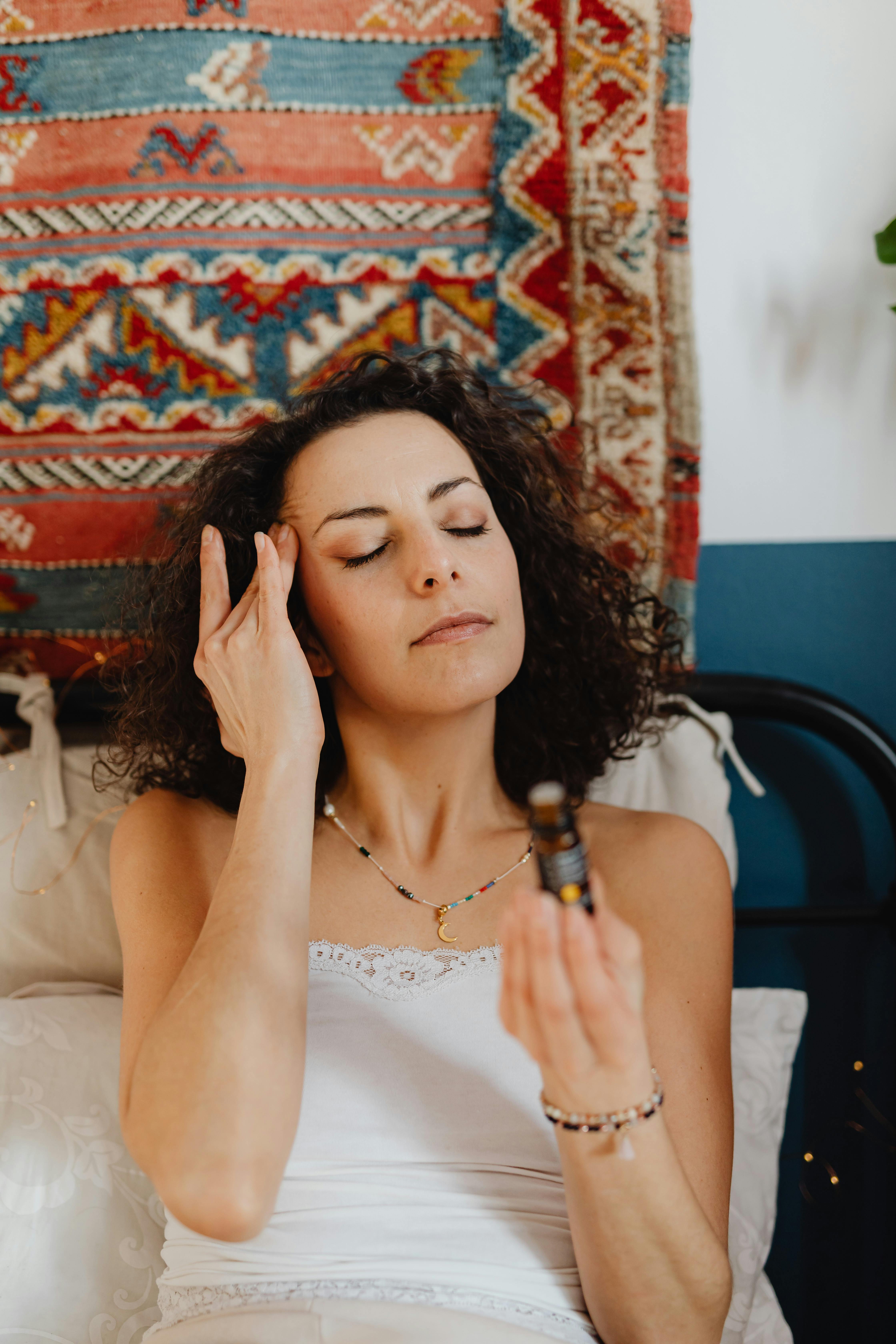 Calm brunette woman enjoying a relaxation routine with essential oils at home.