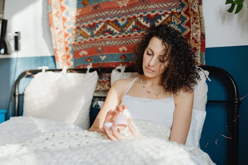 Woman Sitting in Bed and Using a Cosmetic Product 