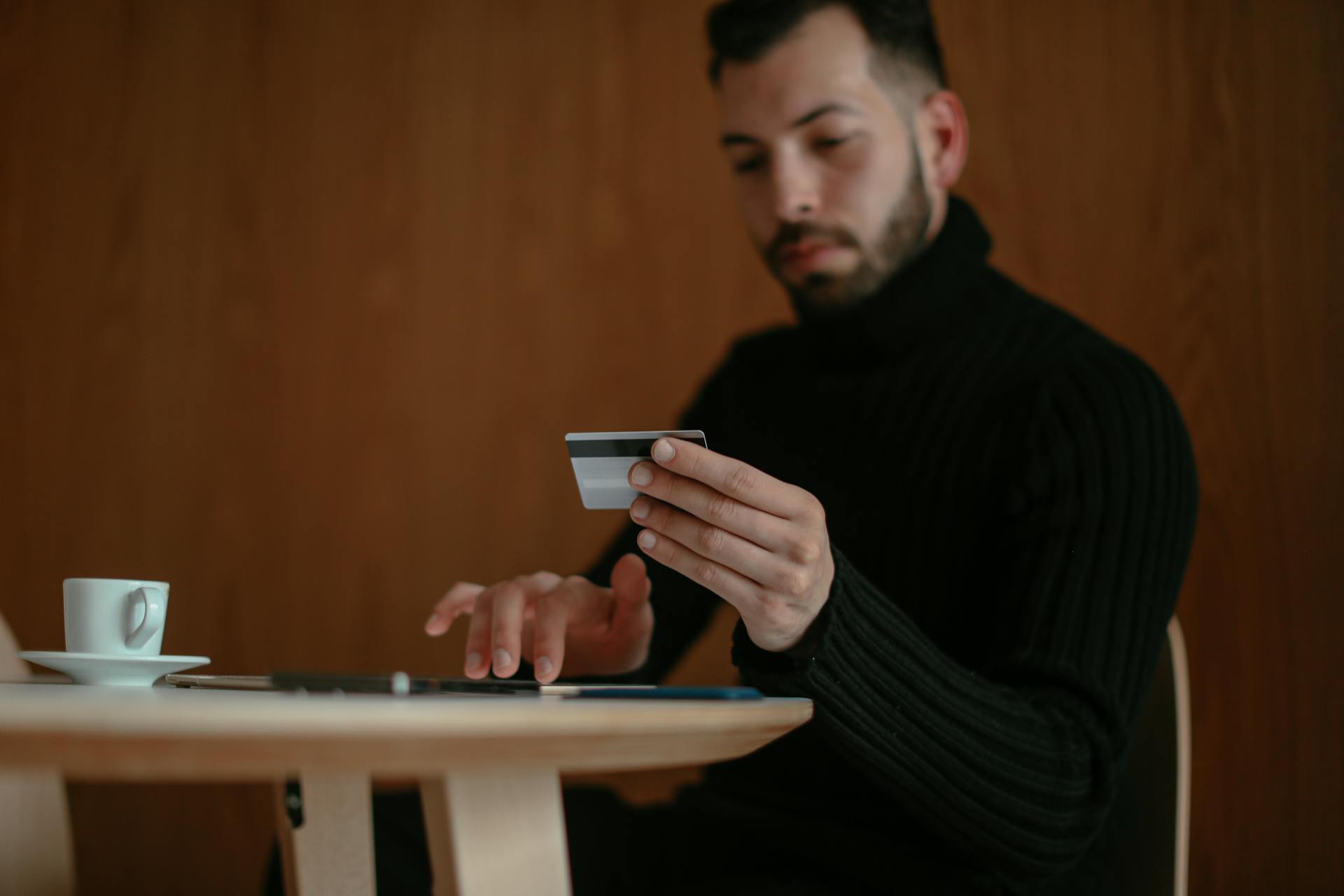 Focused man in café using tablet and credit card for online shopping.