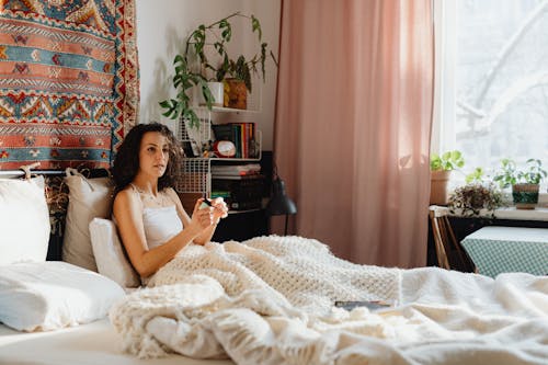 Free Woman Relaxing under Blanket in Bed Stock Photo