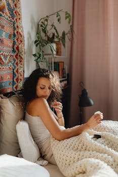Woman enjoying a peaceful morning with warm sunlight in a cozy bedroom setting.