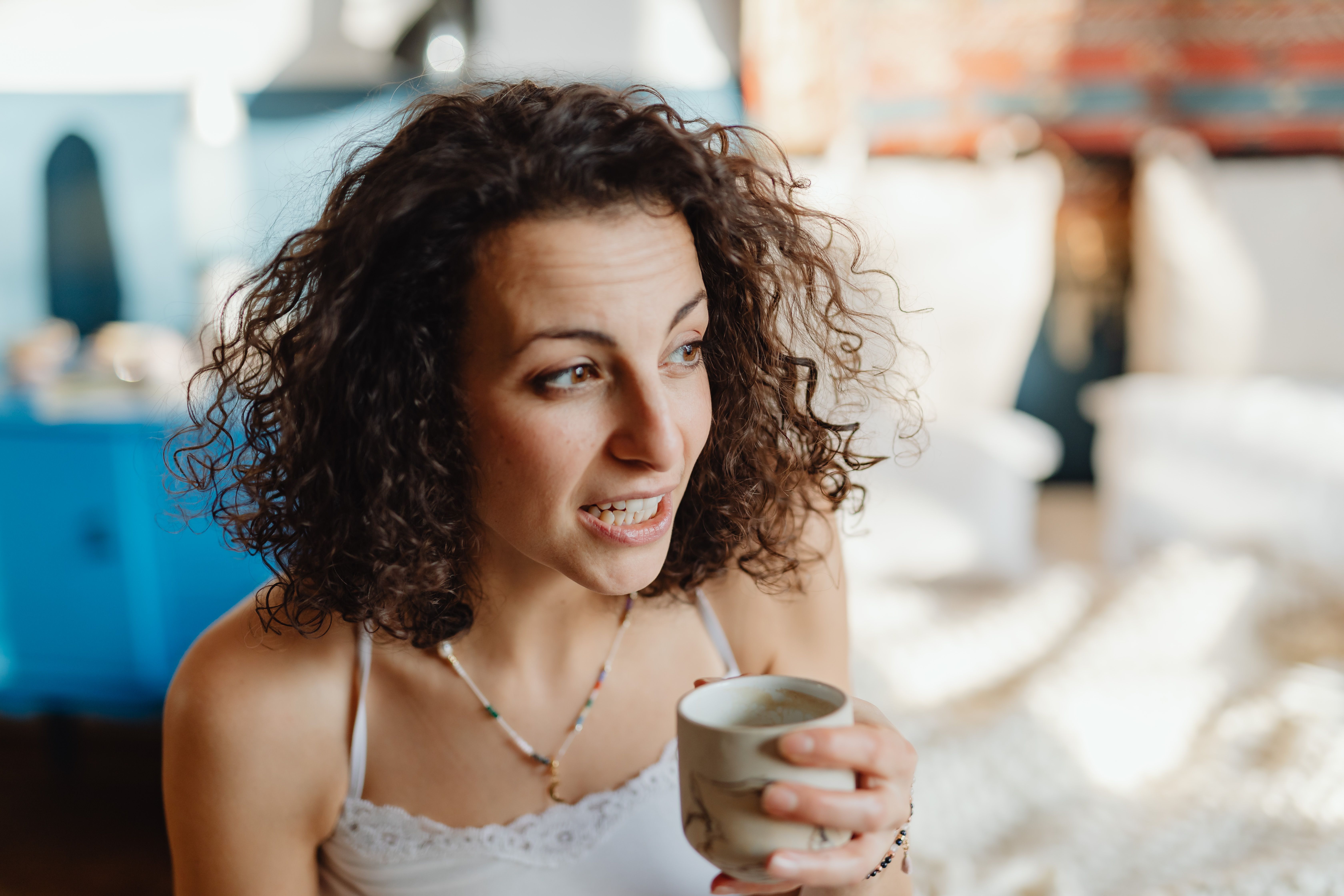 Young woman smiling while enjoying fresh coffee, representing youthful caffeine metabolism