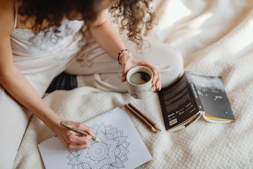 A Woman Holding a Cup of Coffee while Doing an Artwork