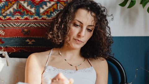 A woman enjoying leisure time writing in her journal in a cozy bedroom setting.