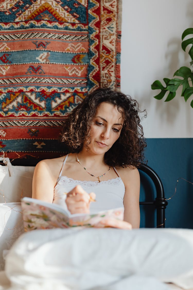 Woman Sitting In Bed And Writing In A Journal 