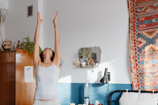 A woman practicing yoga indoors, stretching with arms raised, embracing wellness.